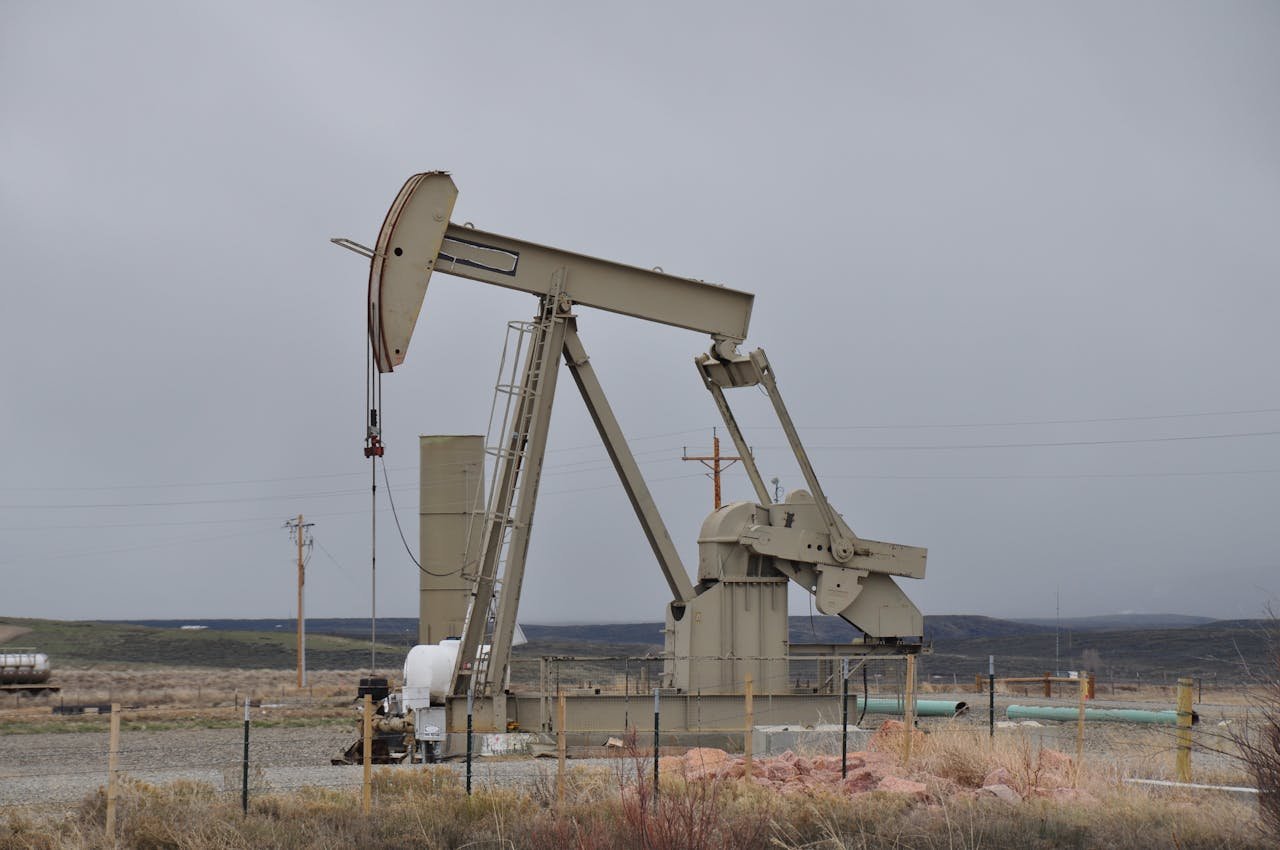 About Oil pumpjack surrounded by barren landscape under overcast skies, showcasing industrial machinery.